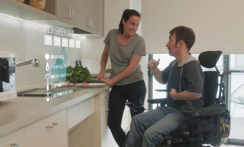 A care worker discusses meals with a person using a wheelchair in the kitchen.