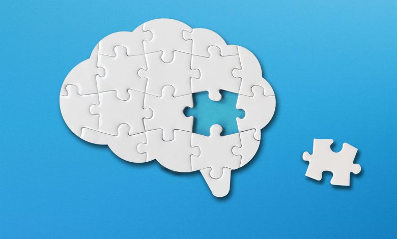 Brain shaped white jigsaw puzzle on blue background, a missing piece of the brain puzzle, mental health and problems with memory