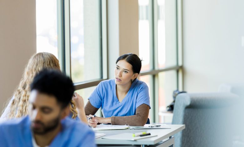 Working together at the library, the young adult female nursing student listens to her unrecognizable female friend.