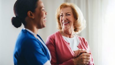 A smiling healthcare professional tends to an elderly woman, creating a moment of trust and care, showcasing a compassionate relationship in a warm and well-lit setting.