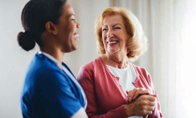 A smiling healthcare professional tends to an elderly woman, creating a moment of trust and care, showcasing a compassionate relationship in a warm and well-lit setting.