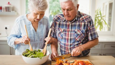 Senior couple preparing salad in kitchen