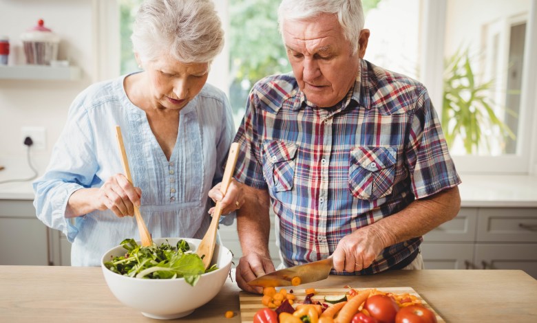 Senior couple preparing salad in kitchen