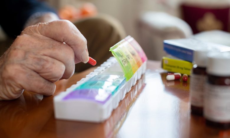 Close Up Of Senior Man Organizing Medication Into Pill Dispenser