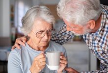 Old senior man comforting his depressed illness wife, unhappy elderly woman at home need medical help.