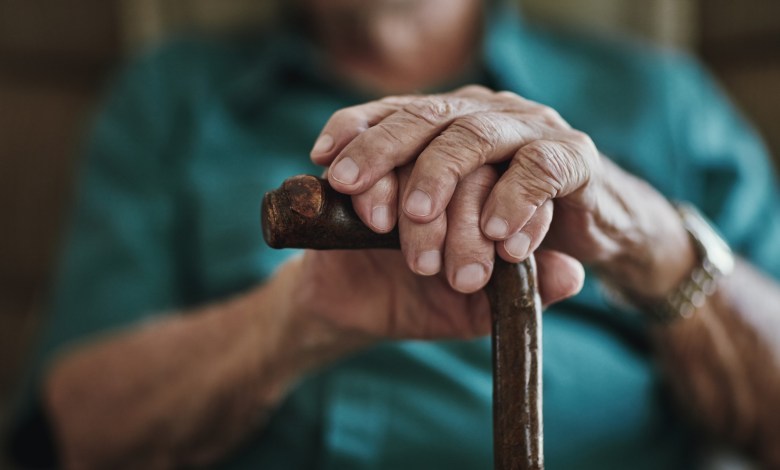 Cropped shot of an unrecognizable man leaning on his walking stick
