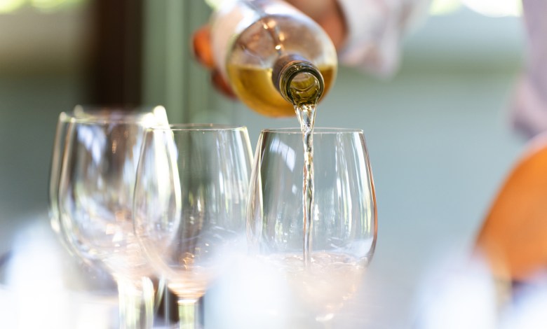 A waiter serves a glass of white wine