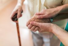 Nurse consoling her elderly patient by holding her hands