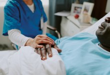 Nurse in scrubs holding hand of elderly patient. Scene portraying compassion, care, and medical support in a clinical setting, with healthcare services being rendered to a senior individual